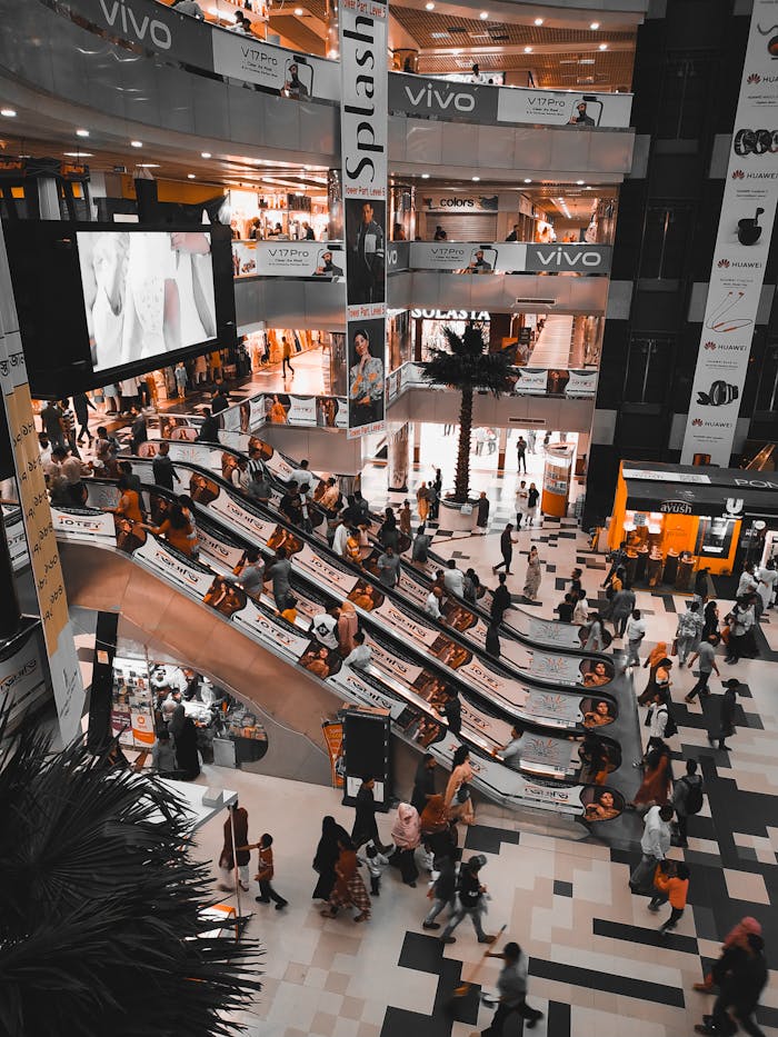 A busy shopping mall in Dhaka with crowds and escalators, showcasing retail vibrancy.