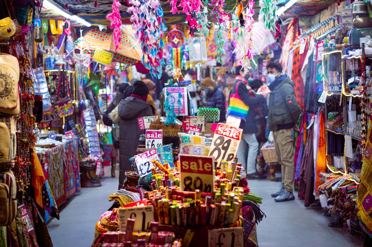 Colorful market aisle in England bustling with shoppers and vibrant textiles.